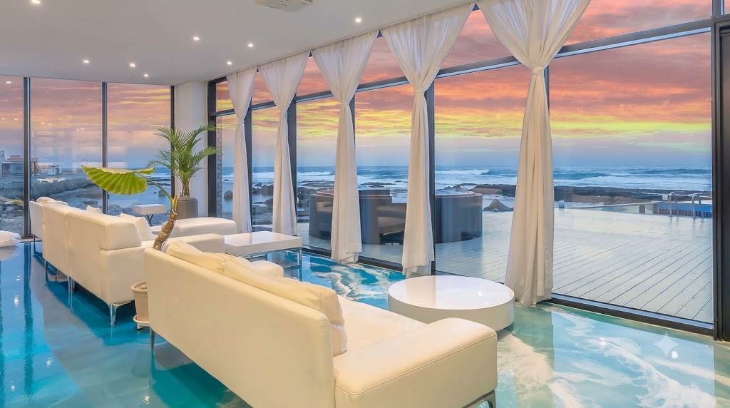 Minimalist all-white luxury interior with floor-to-ceiling panoramic ocean view windows at March Blue Pool Villa Pohang
