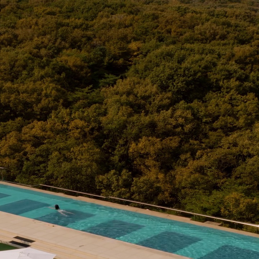 Aerial view of the heated outdoor infinity pool at ANTO Resort Seoul surrounded by the lush autumn forest of Bukhansan National Park