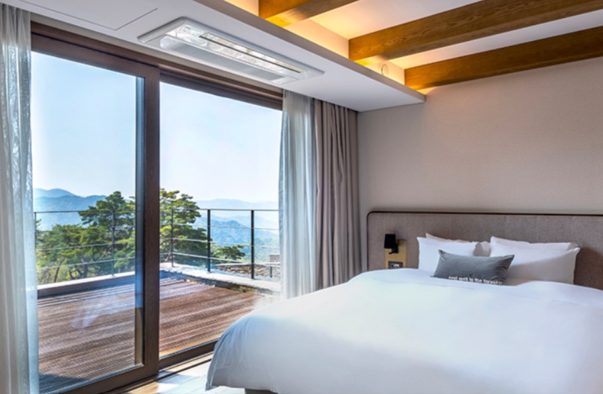 Cozy villa bedroom at Forest Resom featuring floor-to-ceiling windows with panoramic mountain forest views