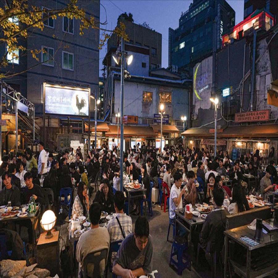Vibrant evening atmosphere at the bustling Jongno Pocha street in Seoul with people enjoying outdoor dining and drinks under lights
